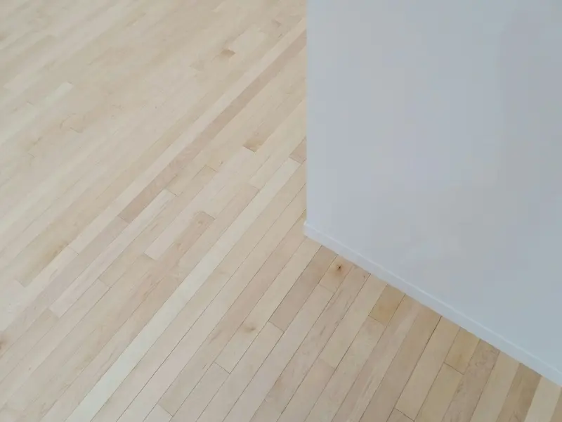 Close-up of wide-plank white oak boards meeting a white baseboard